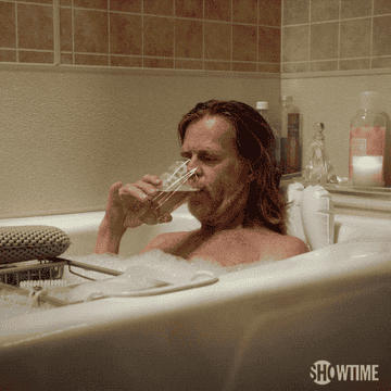 A person enjoys a glass of wine in a bubble bath