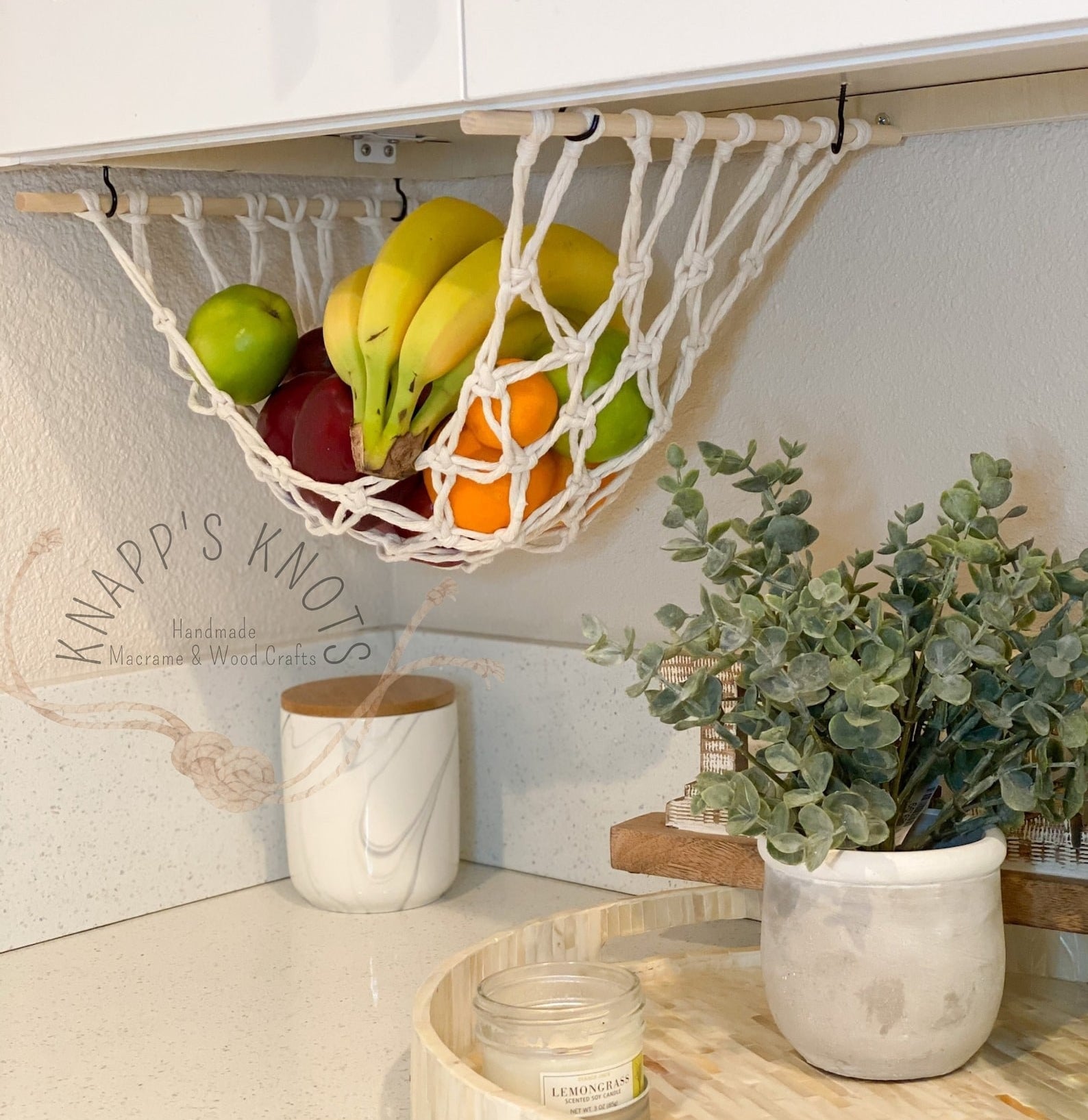 The white macrame fruit hammock hanging under a cabinet