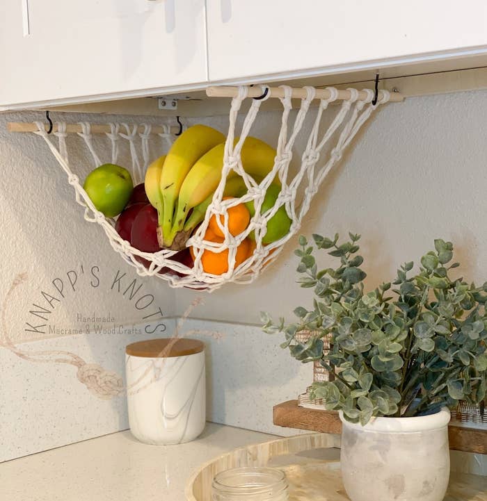The white macrame fruit hammock hanging under a cabinet