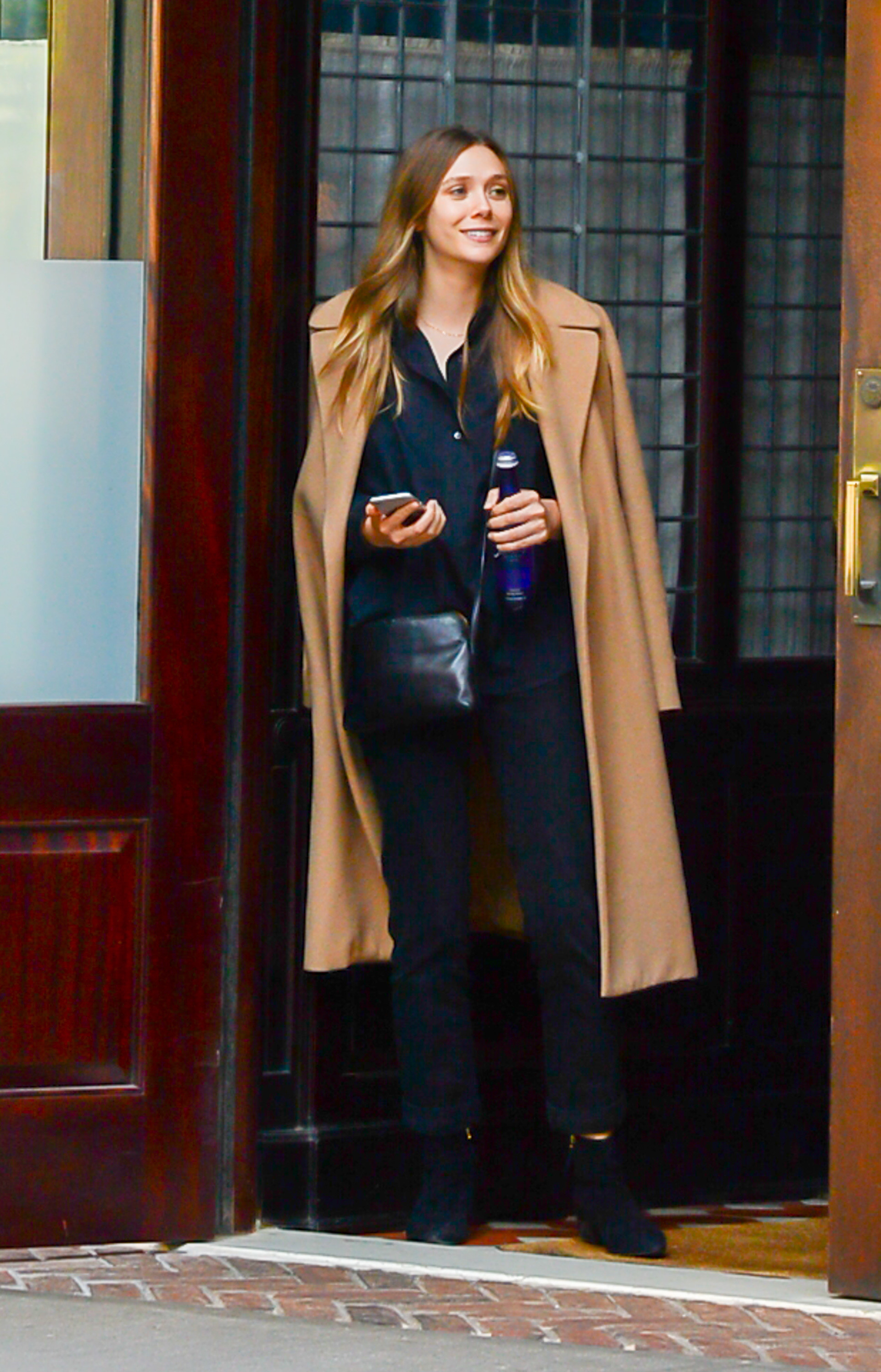 Photo of Elizabeth Olsen in jeans, a button down shirt and a tan coat