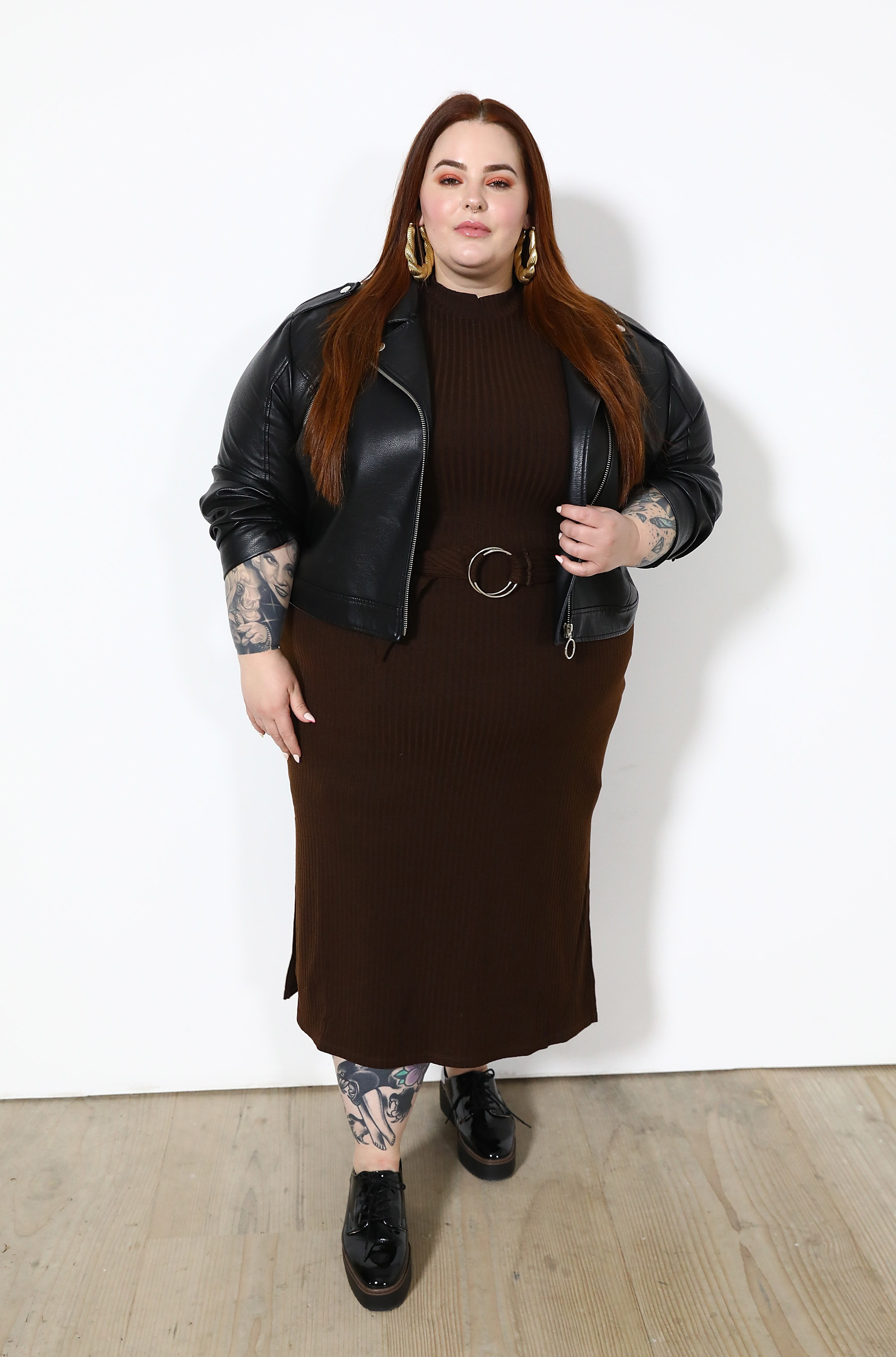Tess Holliday in a brown dress and black leather jacket