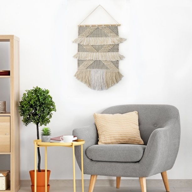 Macrame wall hanging on a wall above living room furniture.