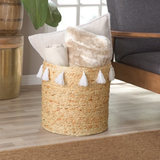 Basket shown holding pillows and a blanket.