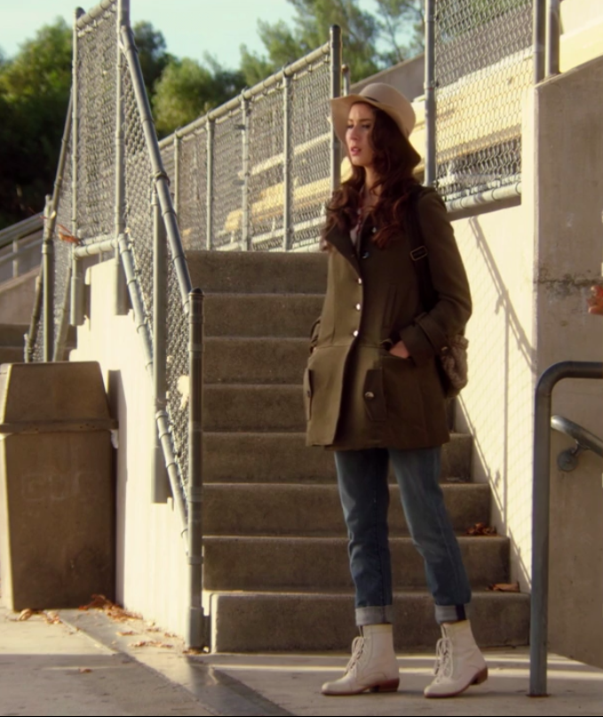 Spencer wearing white, laced boots, jeans, and a trench coat