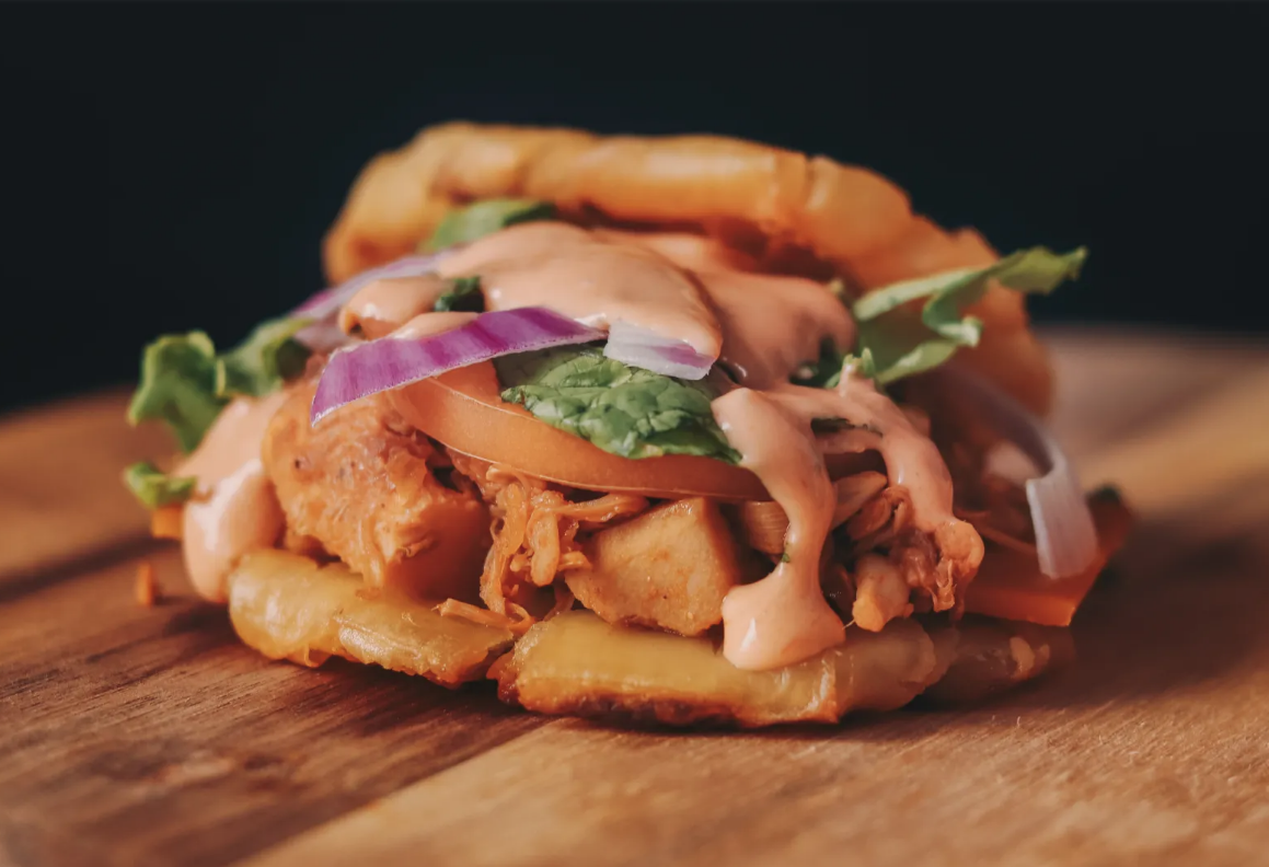 A sandwich made with jackfruit and plantains with its ingredients spilling out