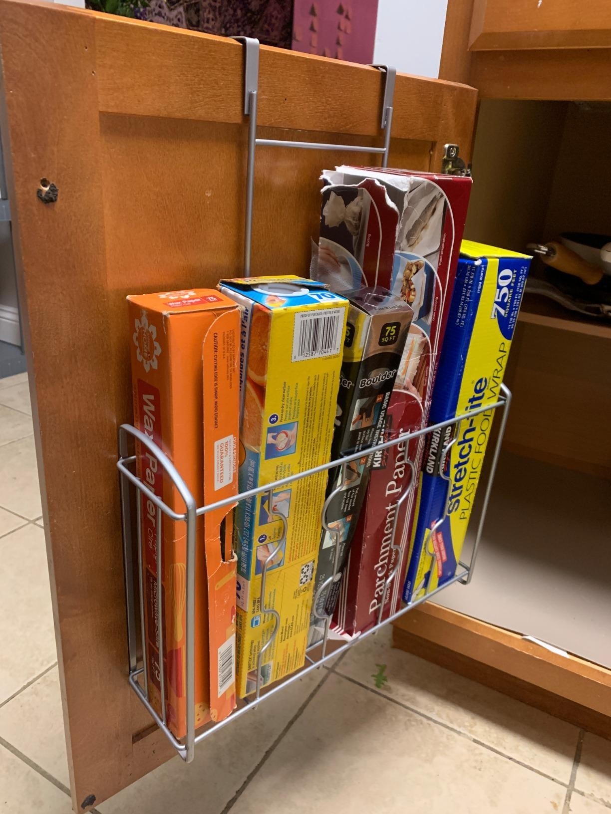 Reviewer photo of the organizer in their cabinet holding plastic wrap boxes