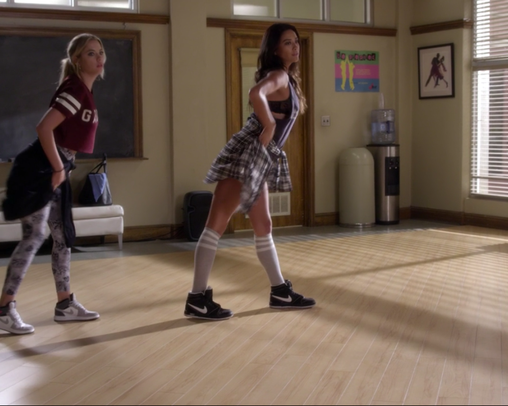 Emily and Hanna wearing coordinated flannel shirts tied around their waists, sneakers, and crop tops