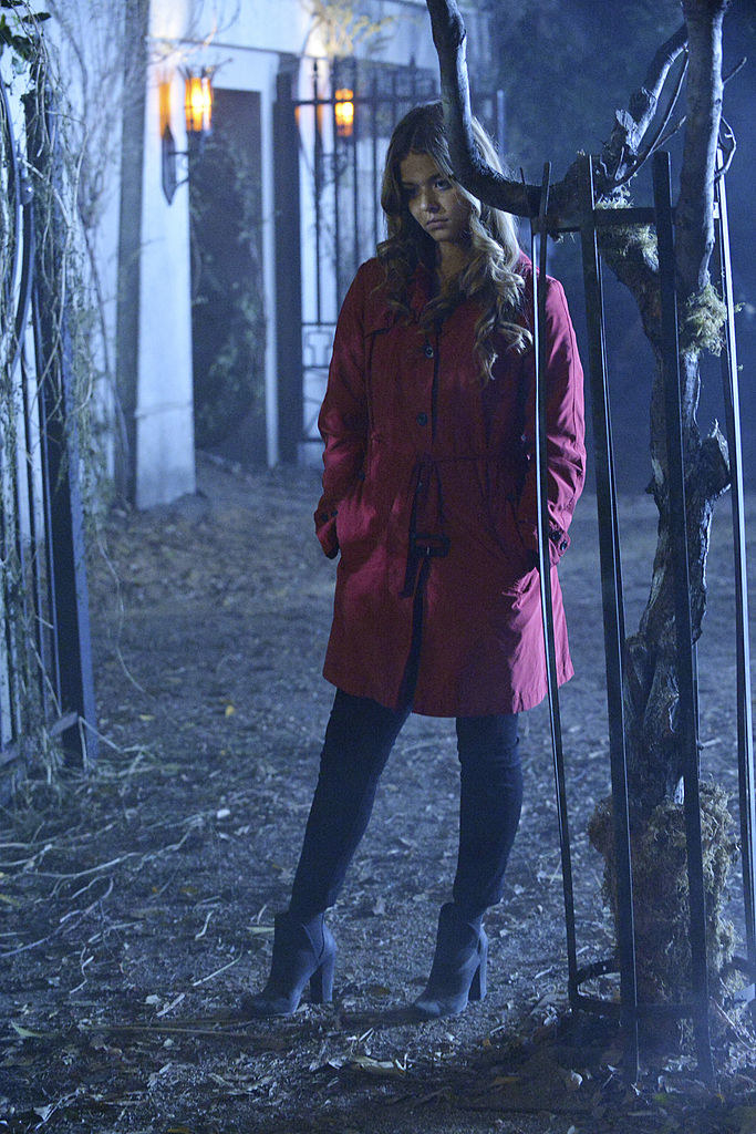 Ali wearing a red trench coat and gray boots