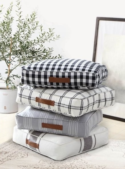 Stack of four floor pillows in different patterns.