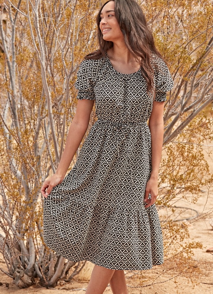 A model wearing a black/white geo printed, puff sleeve, tiered midi dress