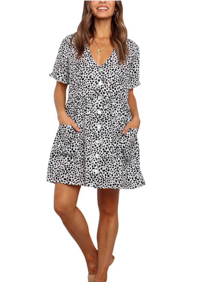 A model wearing a black/white patterned, button-up, short sleeve tunic dress with pockets