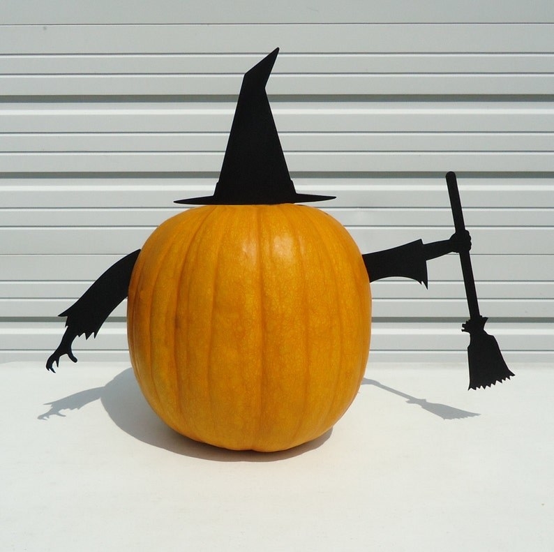 pumpkin with a metal stake witch hat and two metal stake arms, one of which is holding a witch&#x27;s broom