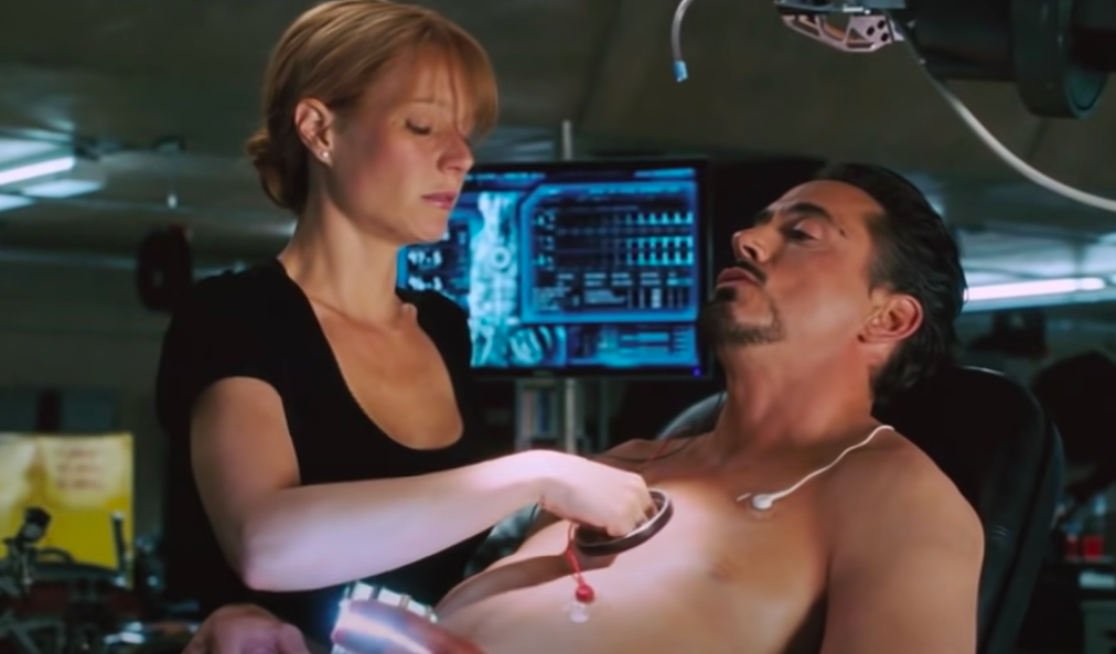 Pepper reaches into the hole in Tony's chest and pulls out the old arc reactor