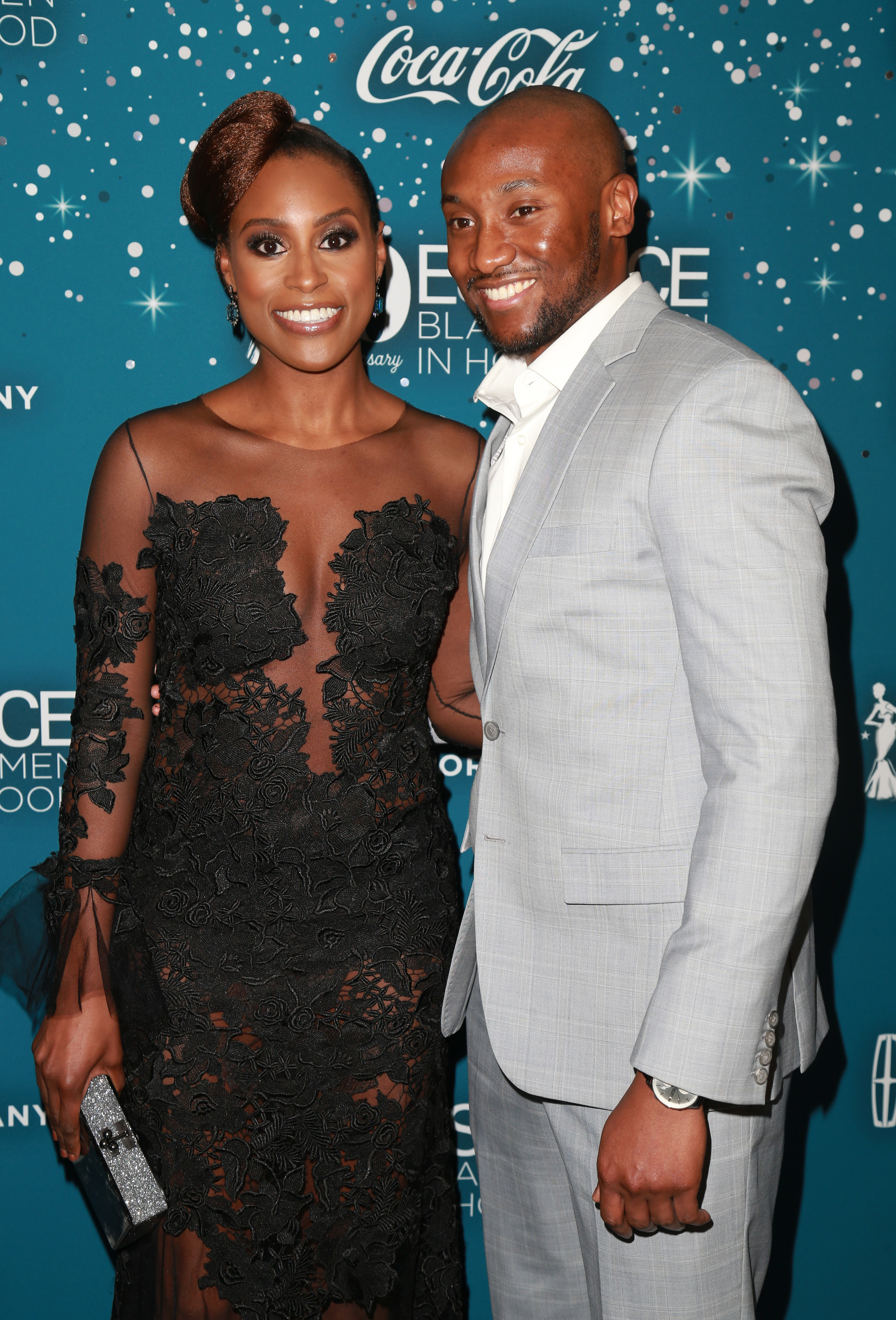 Issa and Louis smiling as they pose for a photo at a red carpet event