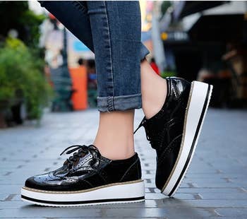 Model wears black oxford platform shoes with cuffed jeans