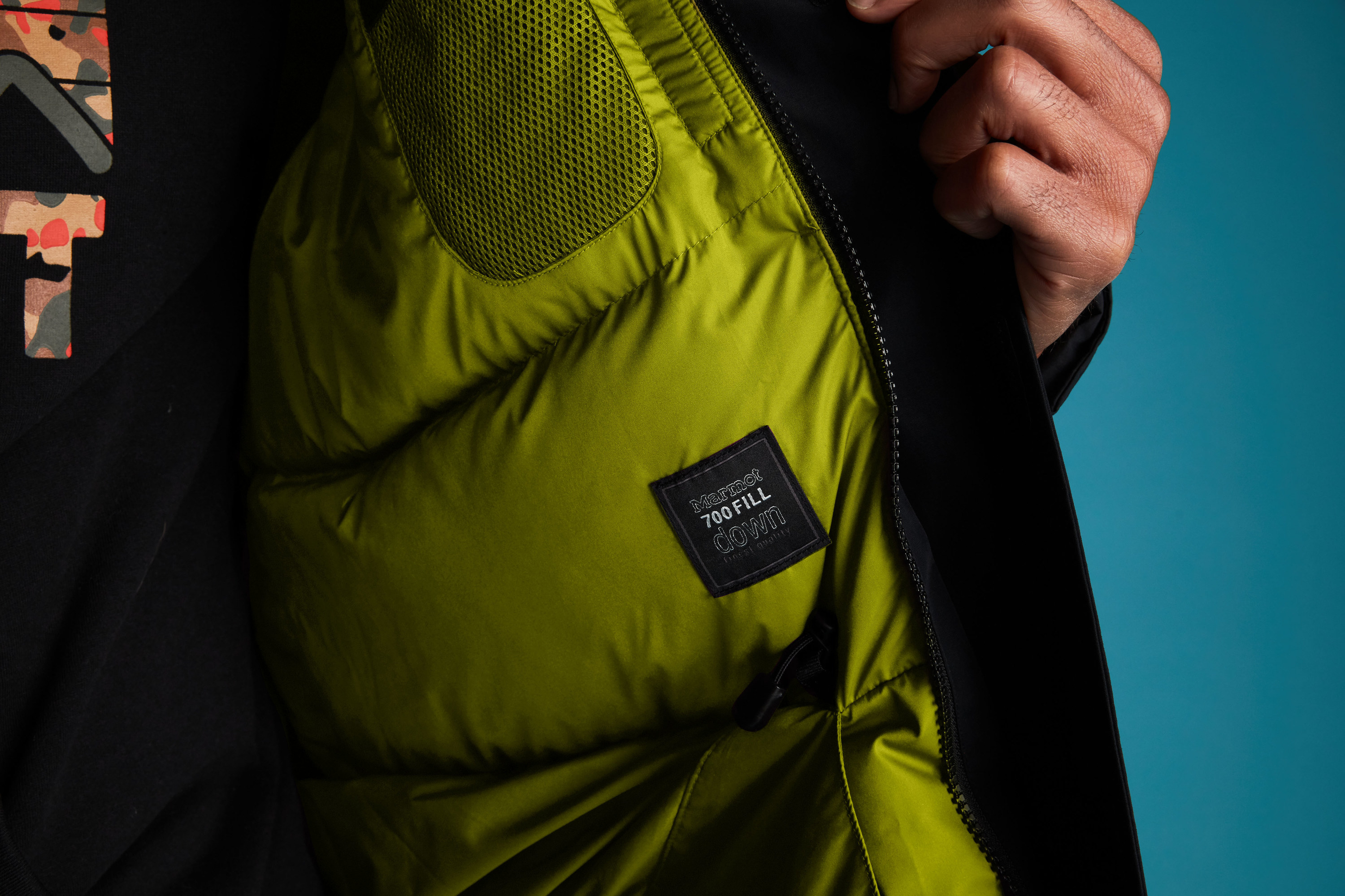 A hand pulls open a black Mammoth parka with citronelle lining, revealing the &quot;700 fill down&quot; tag.