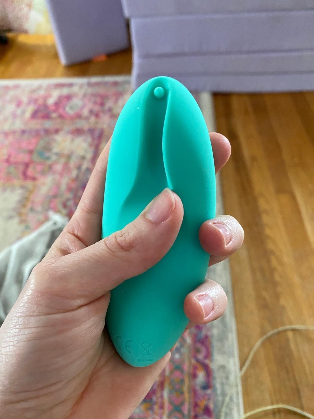 A reviewer holding the small vibrator with a lip on either side