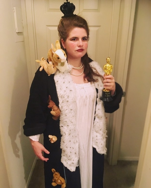 A woman holding a fake Oscar while wearing a robe with stuffed bunnies attached to it