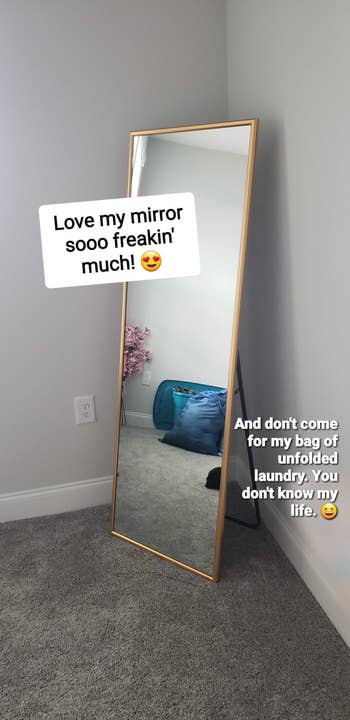 tall mirror with gold frame and a black stand in that back that helps it stand up and lean just slightly