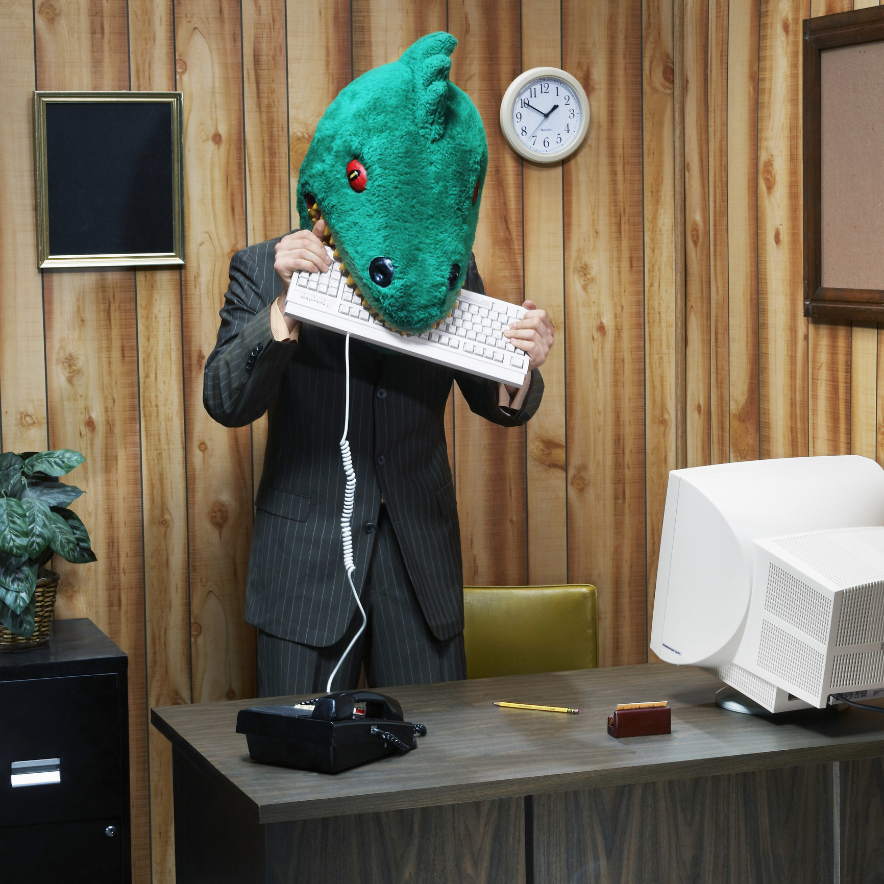 business person in a lizard mask biting a keyboard