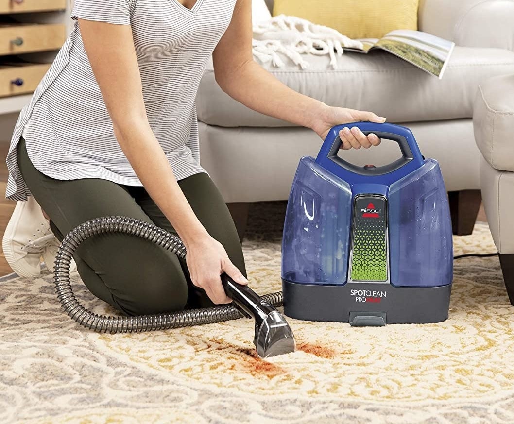 Someone using the vacuum to clean a stain off their carpet