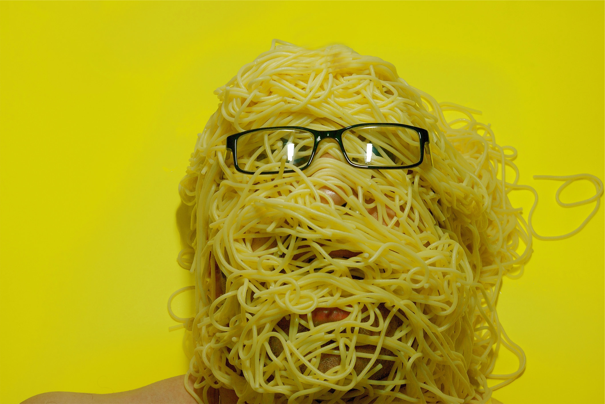 person with their head covered in cooked spaghetti noodles