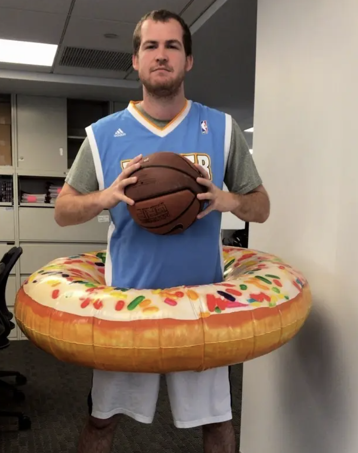 A man dressed as a basketball player while wearing an inflatable tube donut