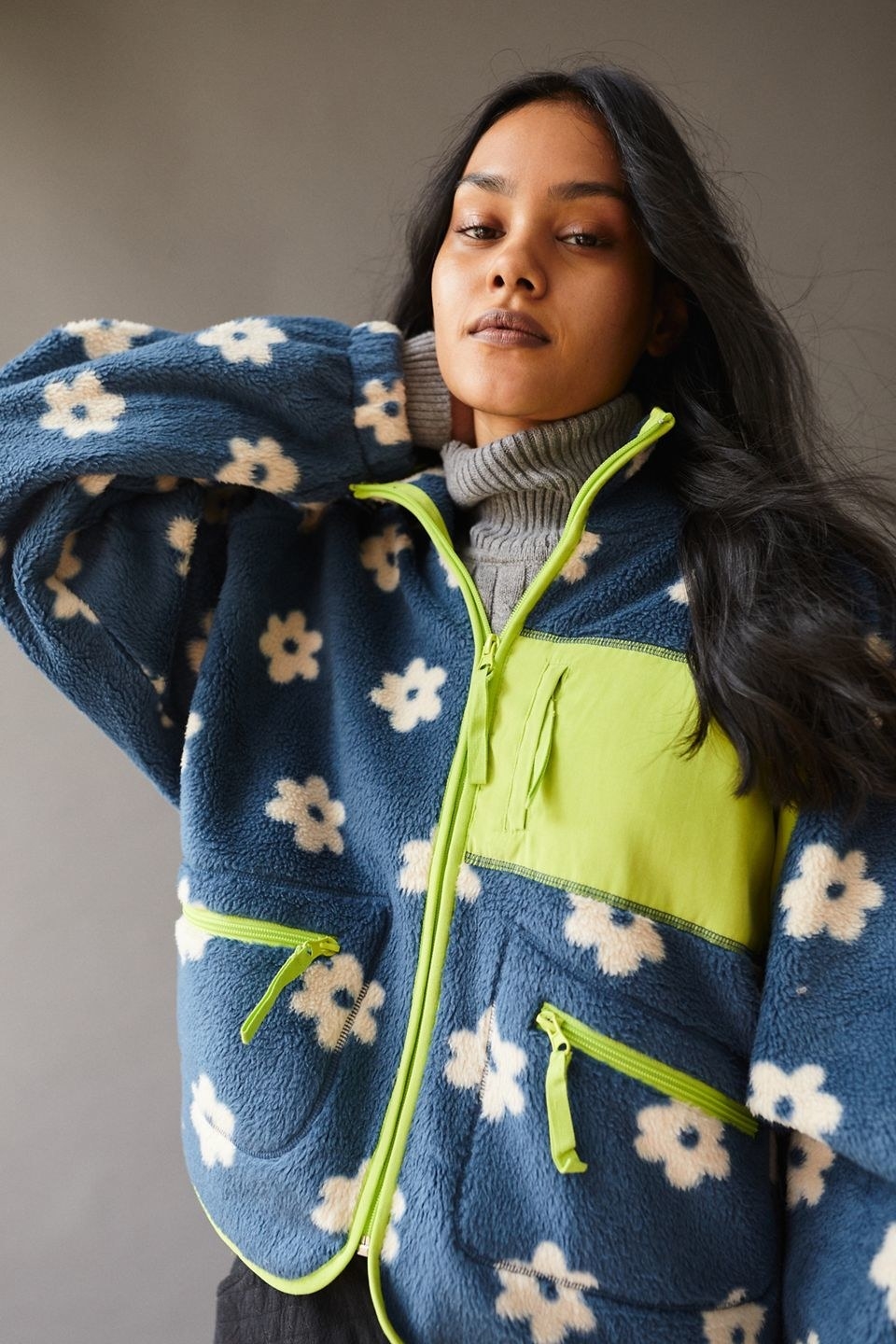 model wearing the blue fleece jacket with white floral design and lime green trim, zippers, and pocket