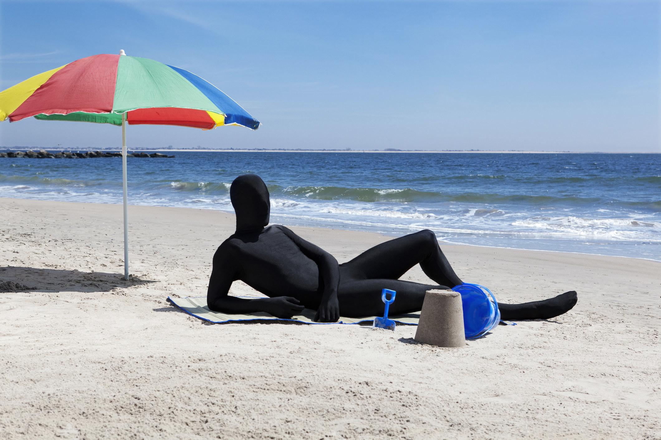 man in morph suit sunbathing on the beach