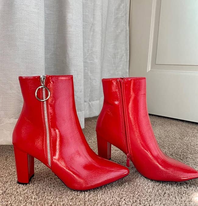 Reviewer photo of the red chunky boots with a pointed heel and a zipper on the size with a keychain charm on the top