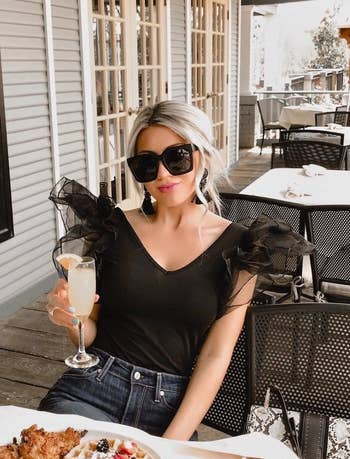 Reviewer wearing the black sleeveless bodysuit with sheer tulle puff shoulders