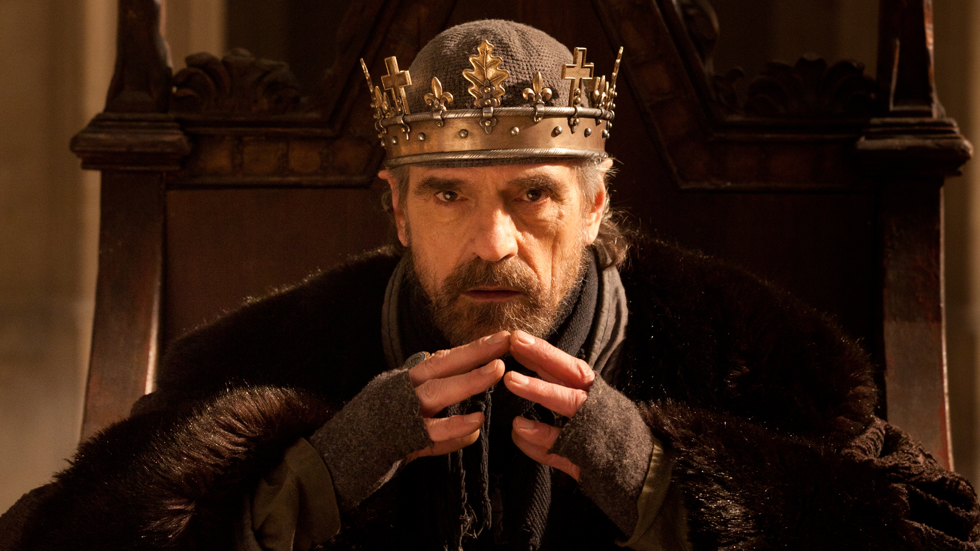 King Henry IV sitting on the throne while wearing his crown