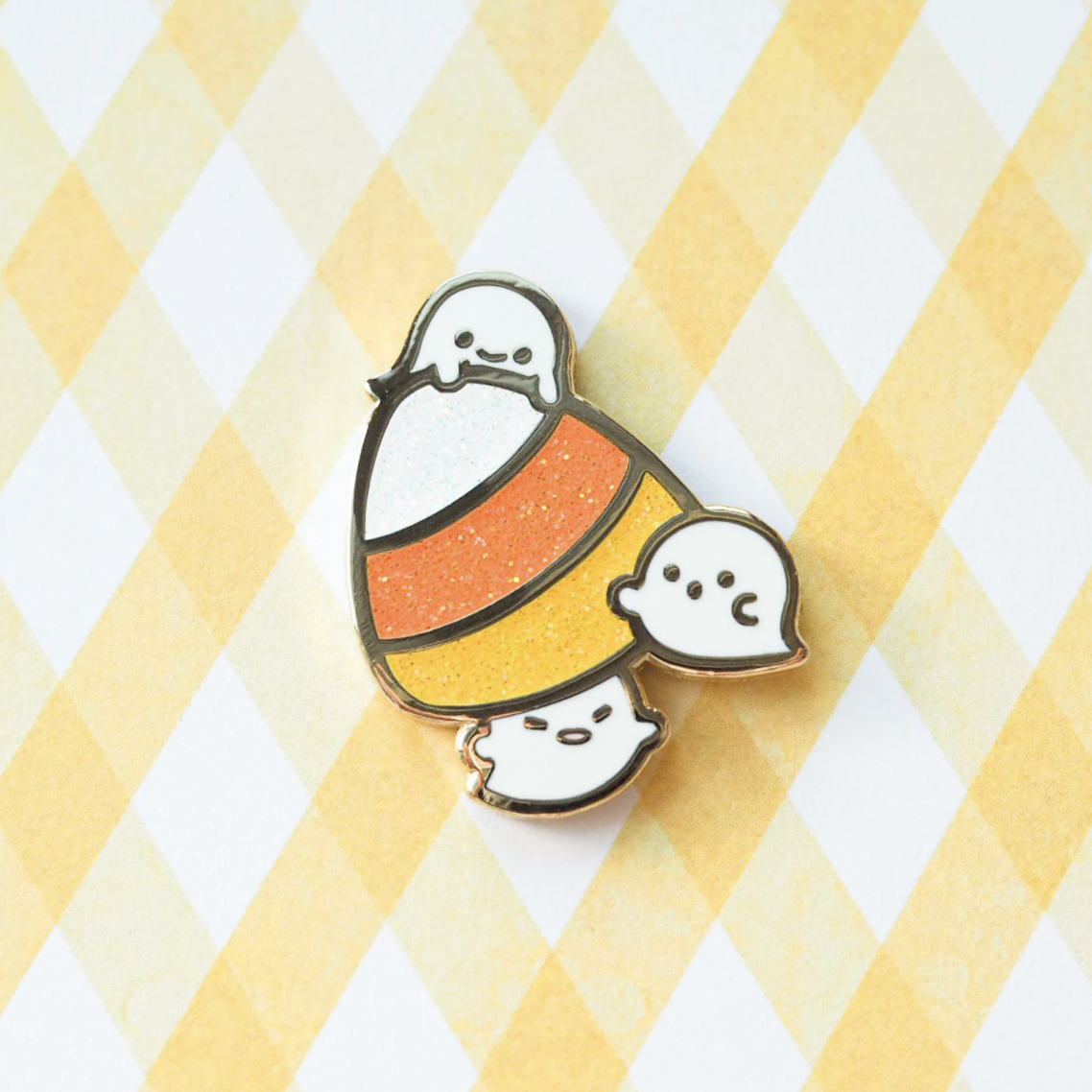 Cute ghosts floating around a sparkly candy corn.