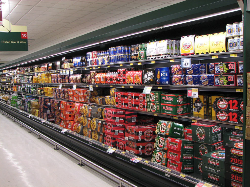 Cans of beer and wine being sold in a supermarket aisle