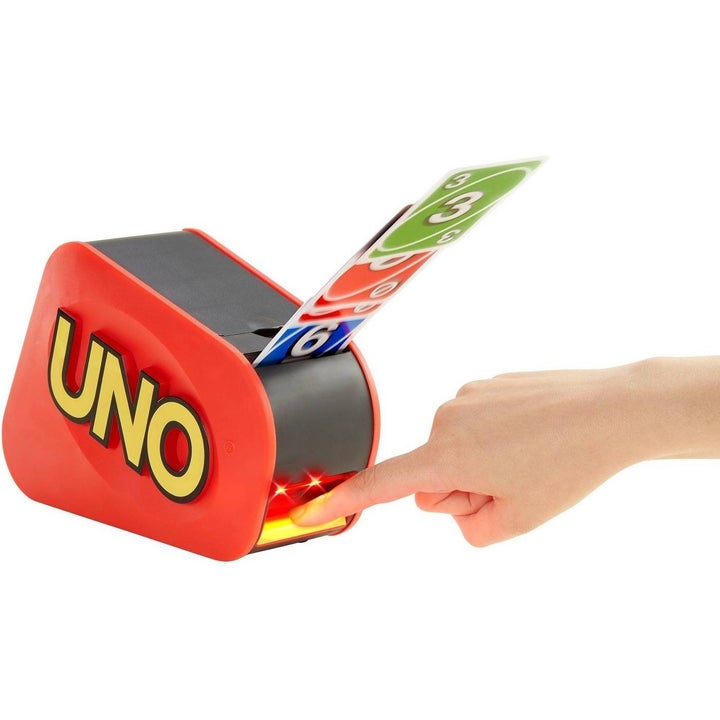 Finger pushing red UNO Attack machine with Uno cards flying out of it