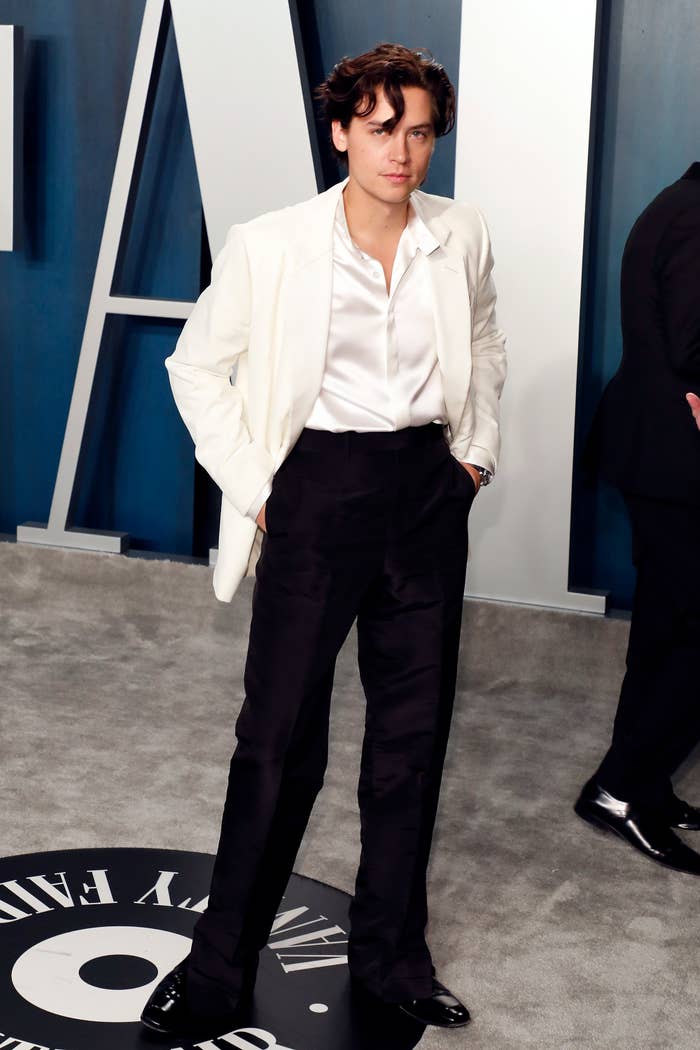 Cole Sprouse poses on the red carpet while wearing a jacket and a button-down shirt