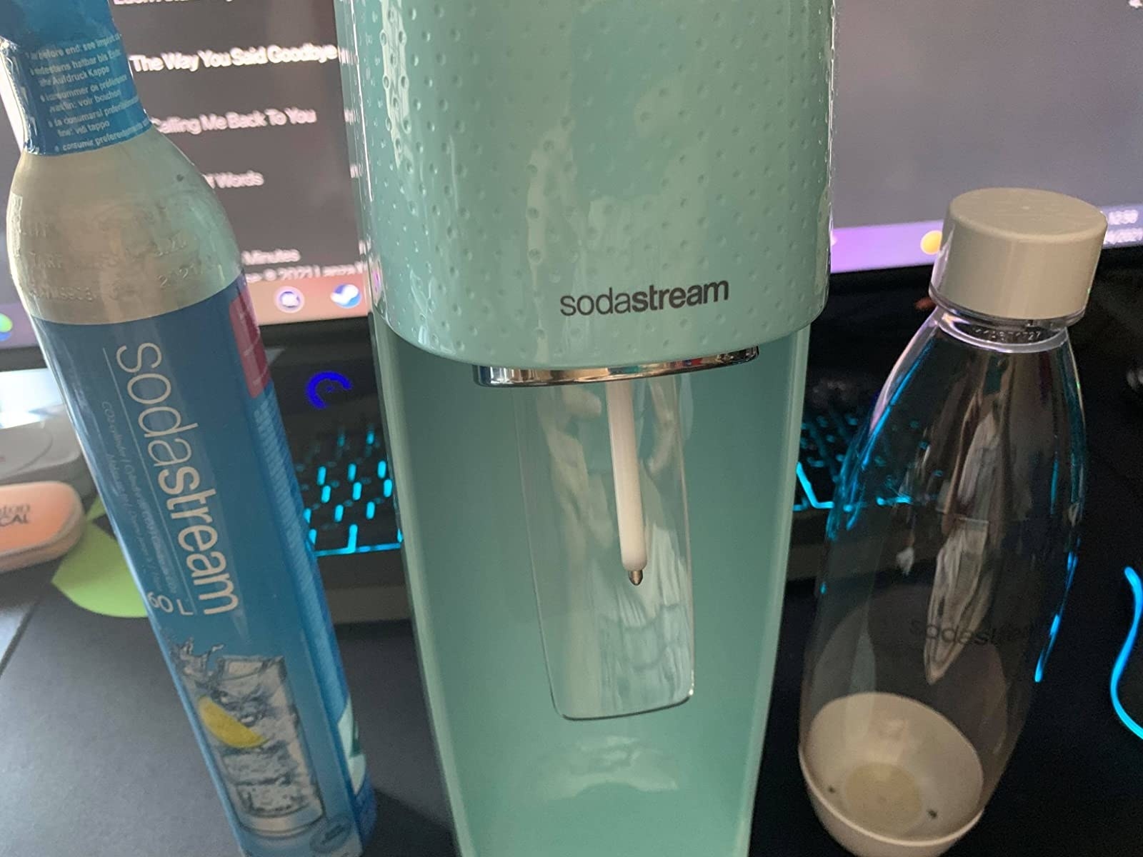 The complete package with a teal-colored SodaStream, fizz-maker, and bottle