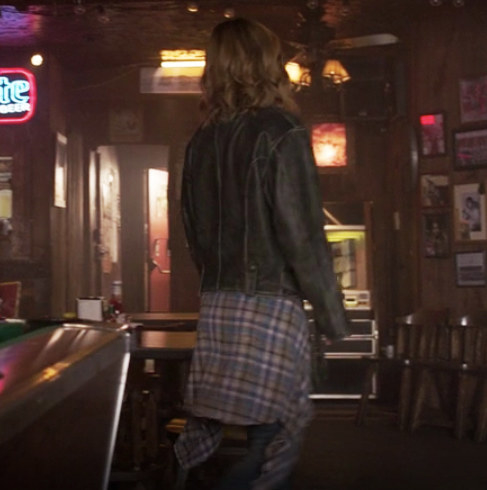 Carol wears baggy jeans and a leather jacket with a flannel tied around her waist