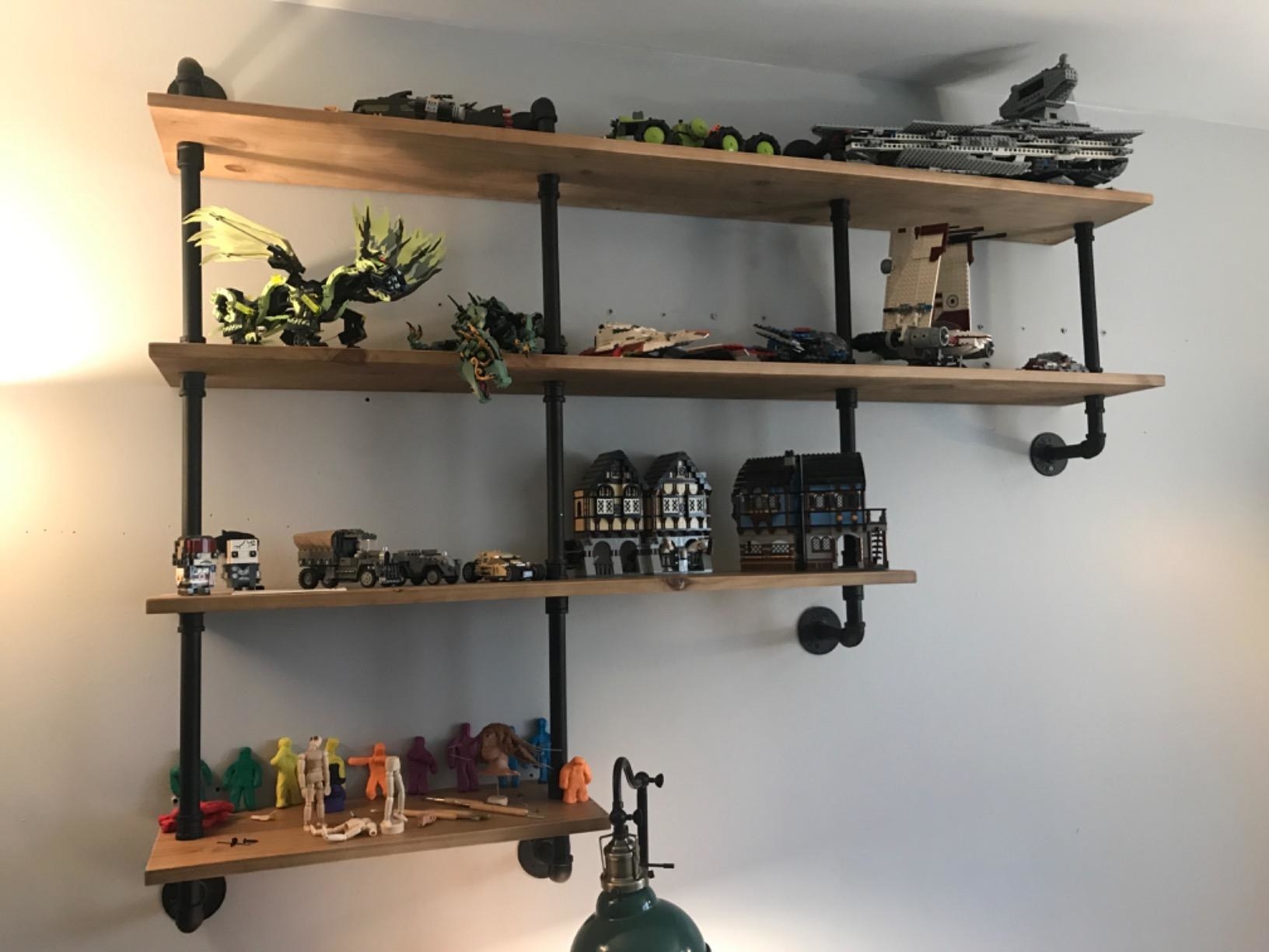 reviewer image of the 4-tiered pipe shelving unit mounted to a wall with LEGO creations on each shelf