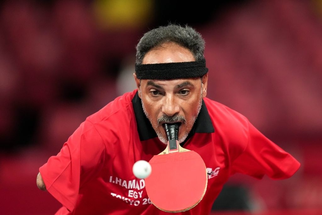 Ibrahim Hamadtou playing table tennis by holding the paddle in his mouth