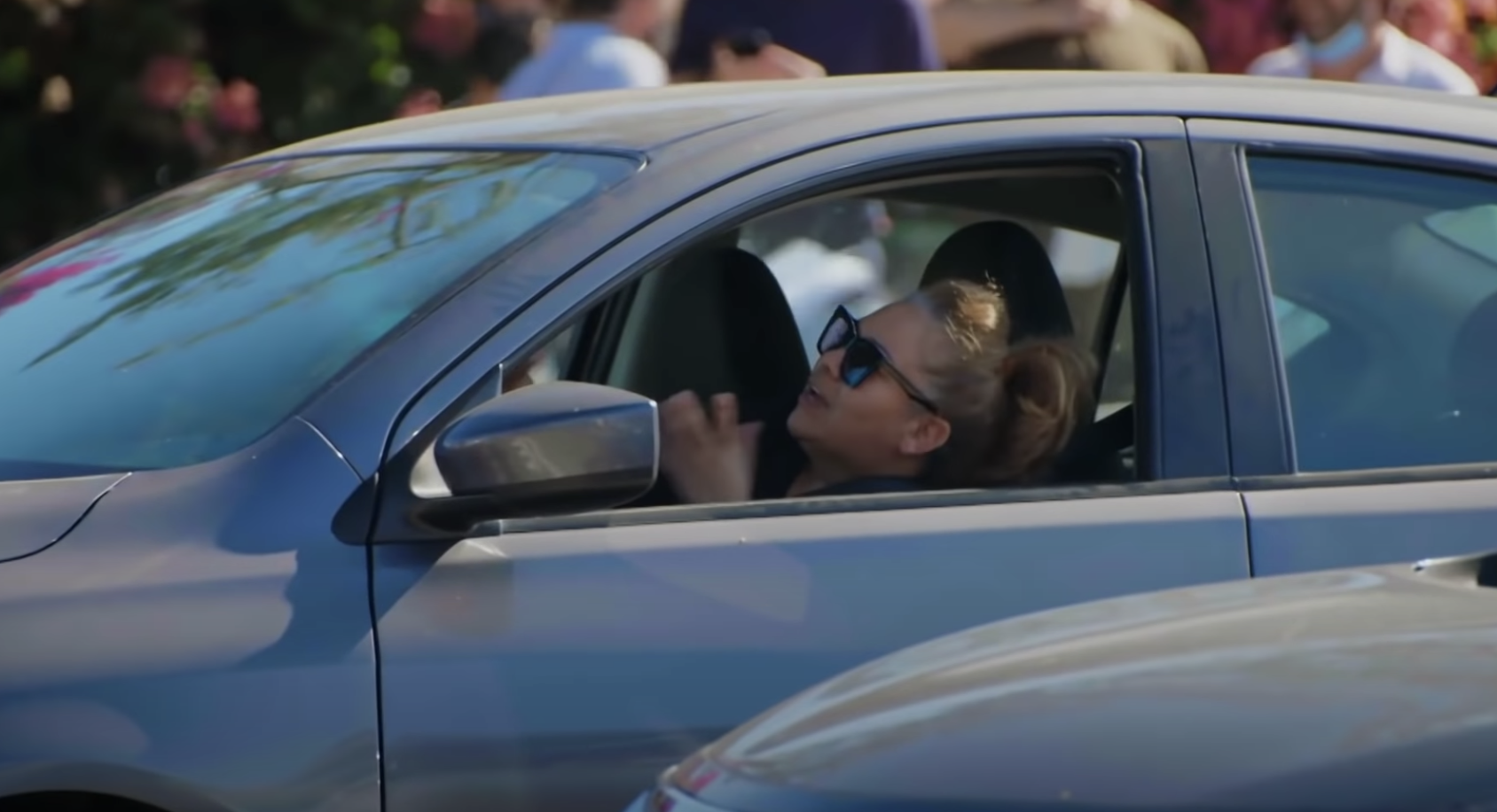 Woman wearing sunglasses and sitting in the driver's seat looking frustrated