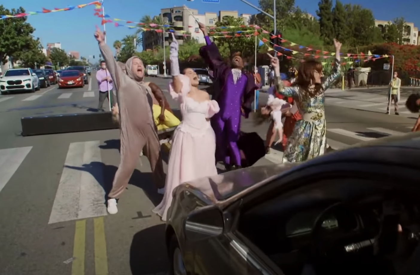 The cast performs in the crosswalk, throwing up their hands