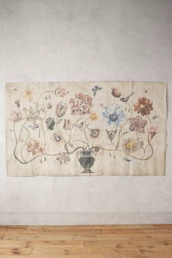 faux aged vase tapestry with renaissance illustration of several flowers 