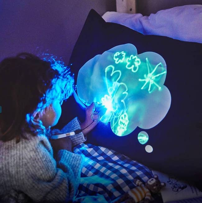Child drawing on a glowing pillow in the dark