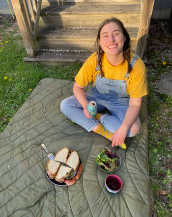 BuzzFeed Reviews editor Rachel sitting on her comfy puffer blanket and a delicious-looking sandwich on a plate. Now you just wait a minute while I call up Rachel to ask why I wasn't invited.
