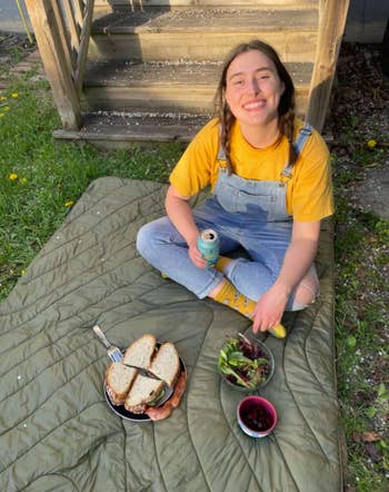 Former BuzzFeed Reviews editor Rachel sitting on her comfy puffer blanket and a delicious-looking sandwich on a plate. Now you just wait a minute while I call up Rachel to ask why I wasn't invited.