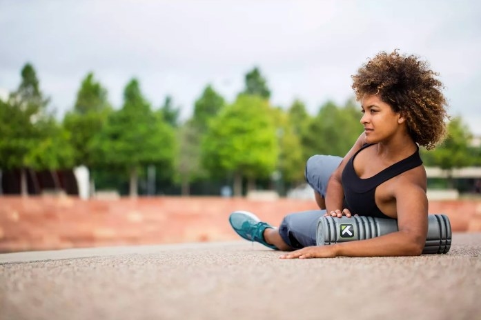 Model using the foam roller to stretch her abdomen and shoulders