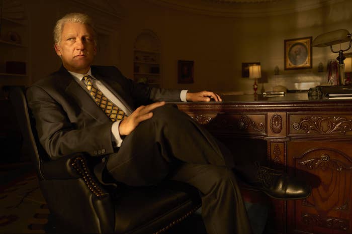 Clive Owen as Bill leaning back in a chair at an office desk