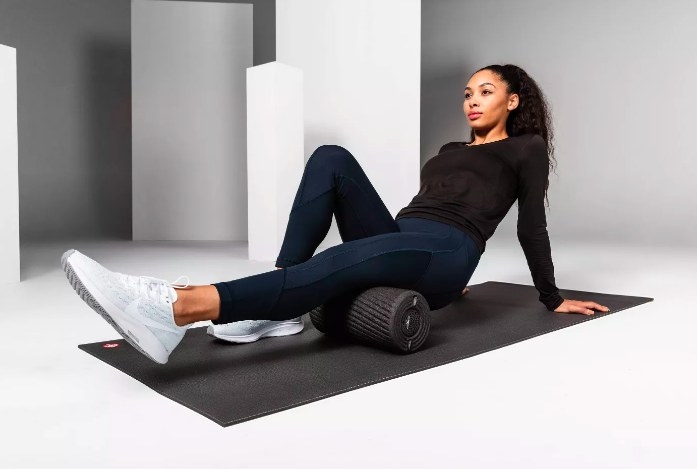 A model using the vibrating foam roller on her hamstring