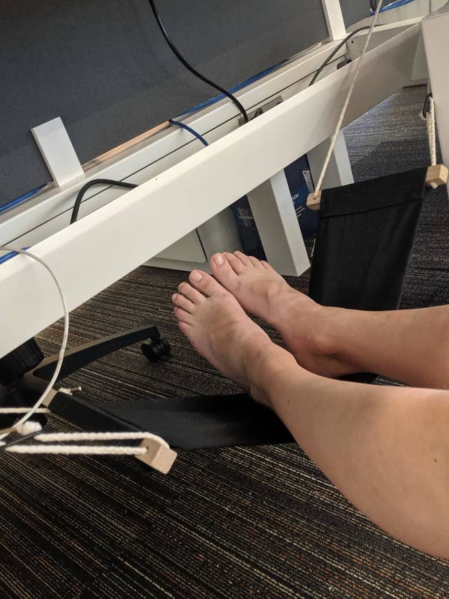 a reviewer with their feet resting on the hammock under their desk setup
